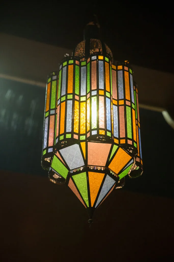 Ornate hanging lamp with glowing multicolored stained glass panels.