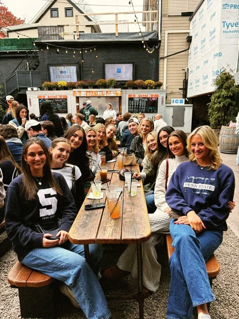 Penn State students smiling at an outdoor bar patio.