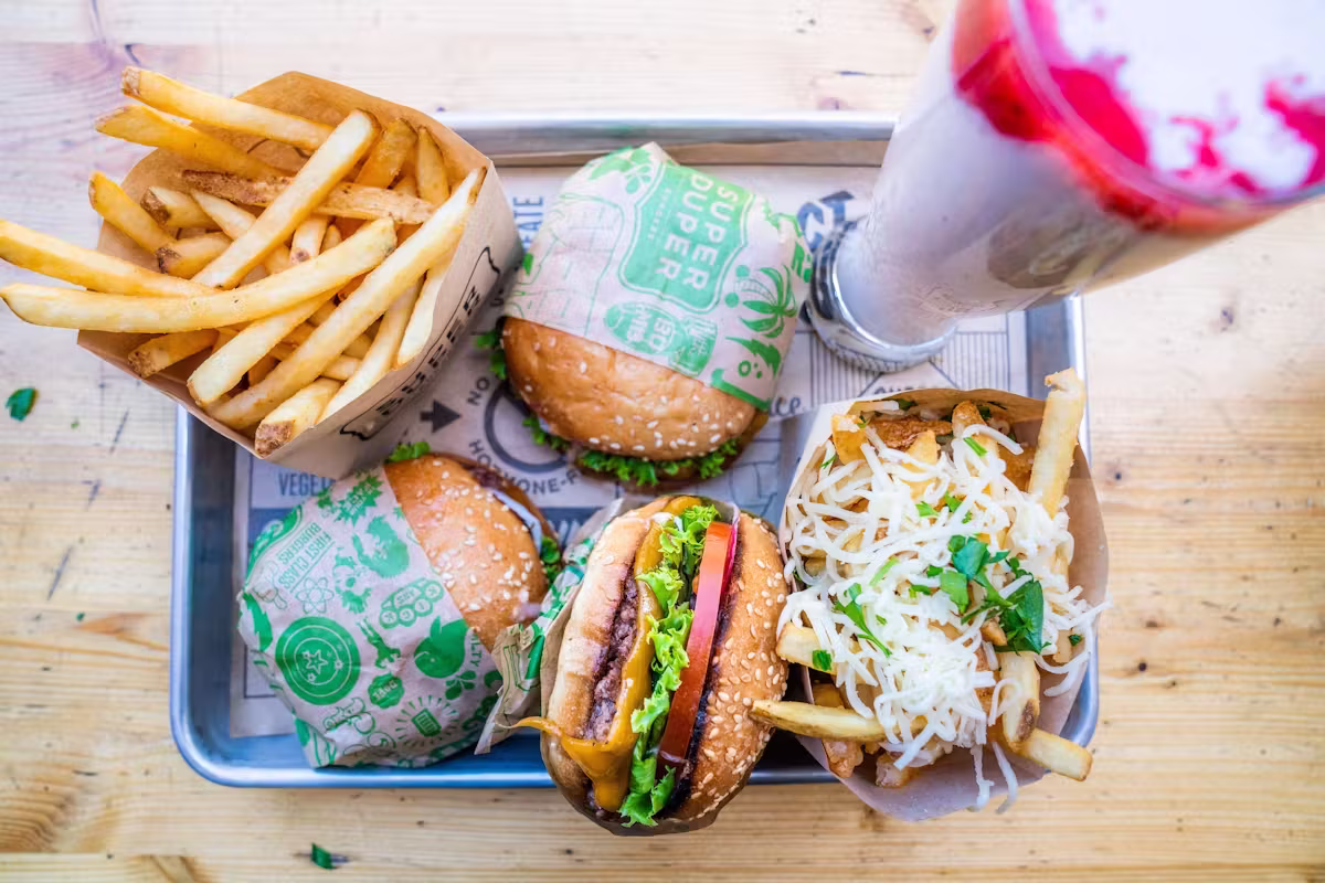 Tray with burgers, plain fries, cheesy fries, and a milkshake.