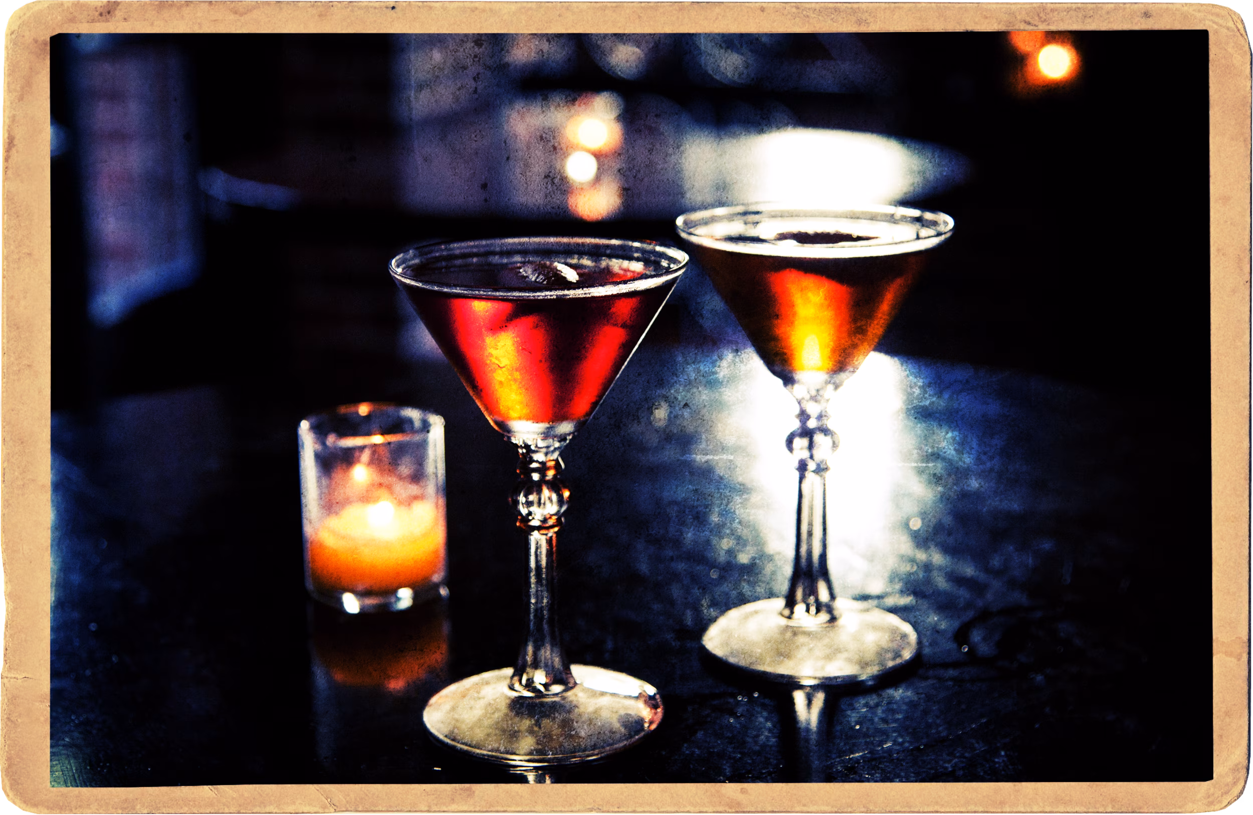 Dark, grainy photo of two red drinks and a lit candle.
