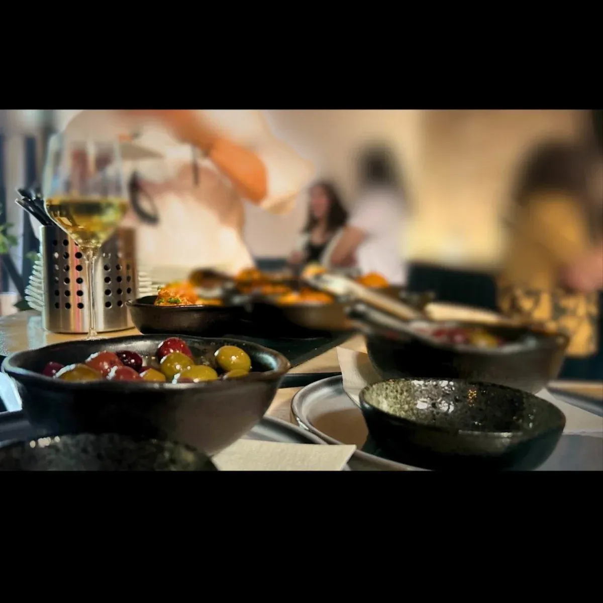Dark bowls of olives and food with wine in a restaurant.