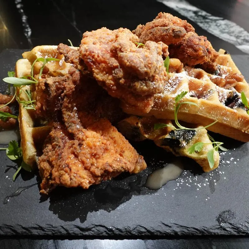 Fried chicken and waffles topped with powdered sugar and herbs.