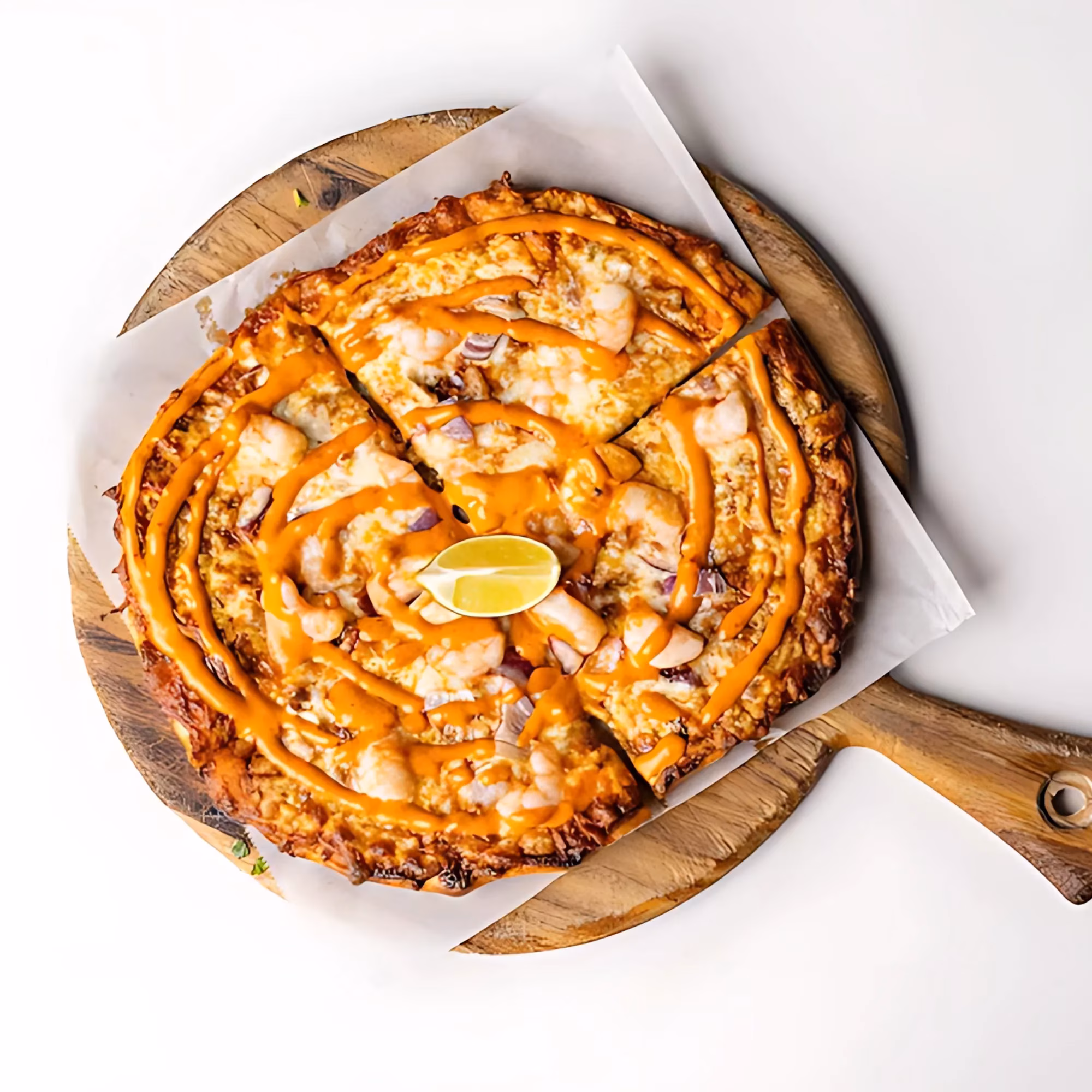 Sliced pizza with shrimp, red onion, orange sauce, and lime.