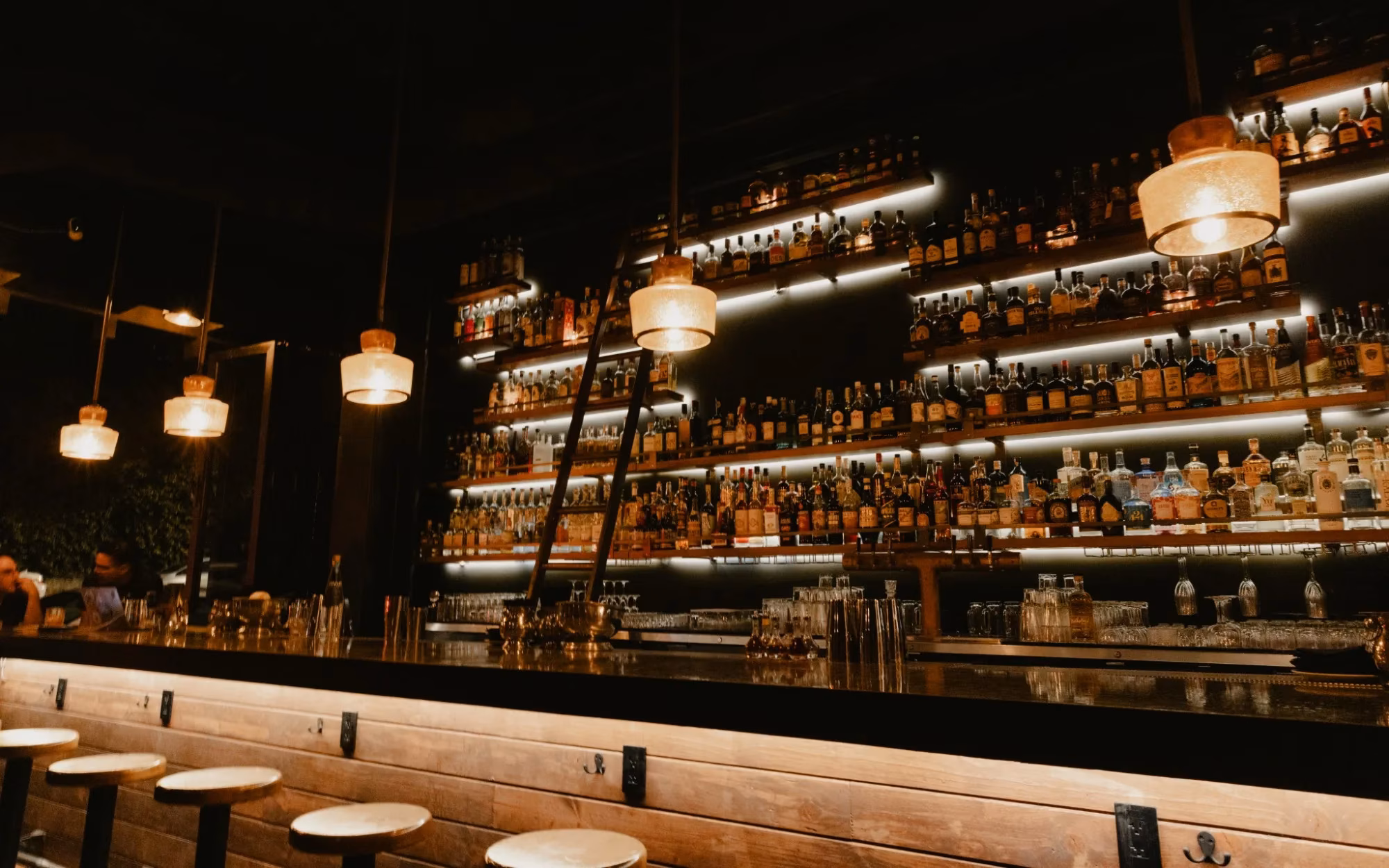 Dark bar with many liquor bottles on backlit shelves.