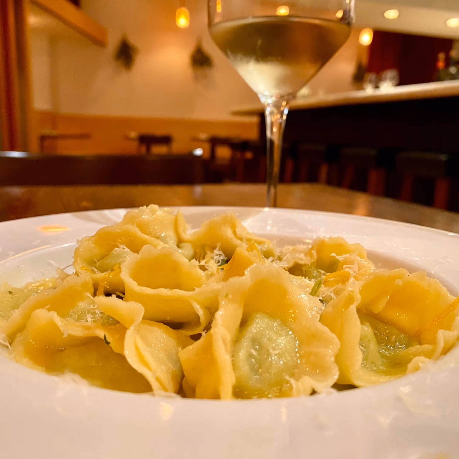 Plate of pasta with grated cheese and white wine.
