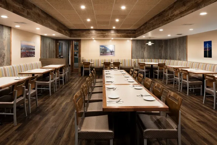 Empty restaurant dining room with communal table and booths.