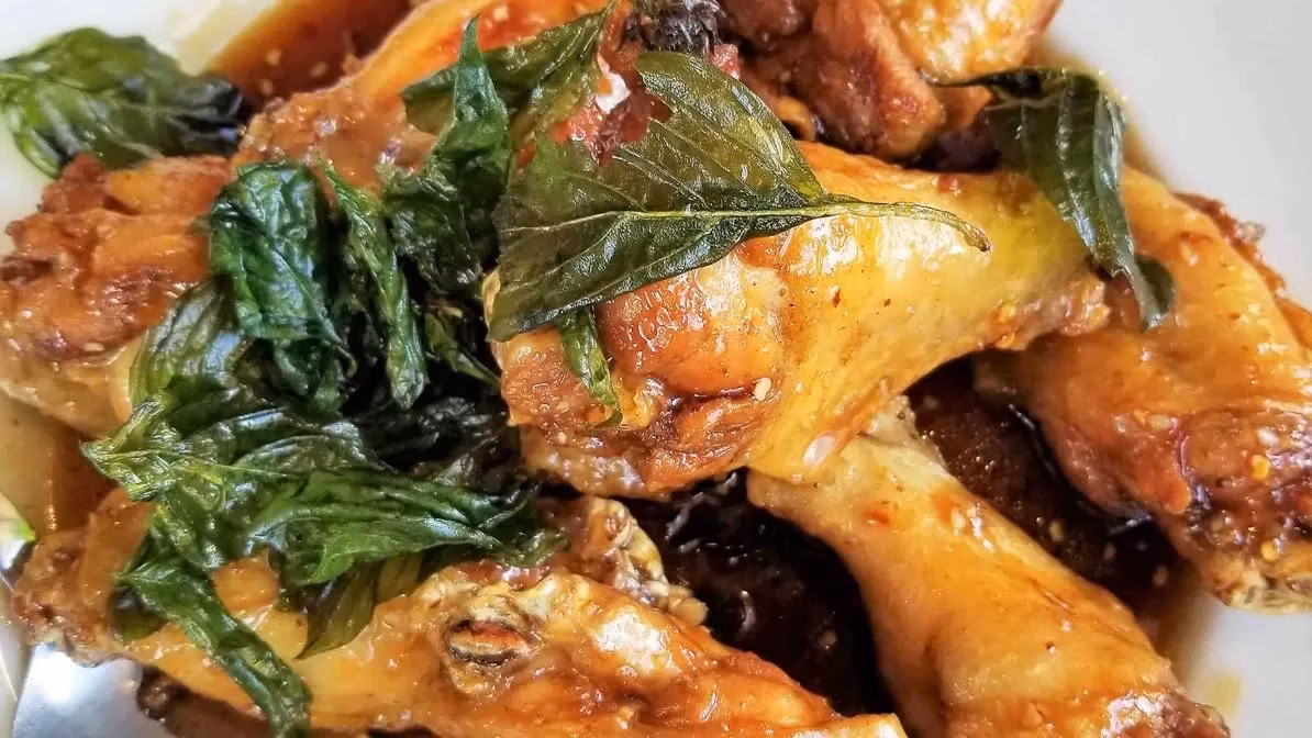 Golden-brown chicken pieces topped with fresh green basil leaves.