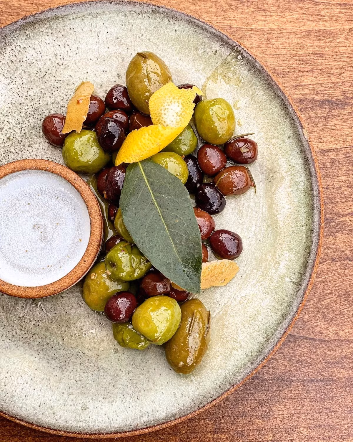 Mixed green and dark olives, lemon peel, bay leaf, small dip.