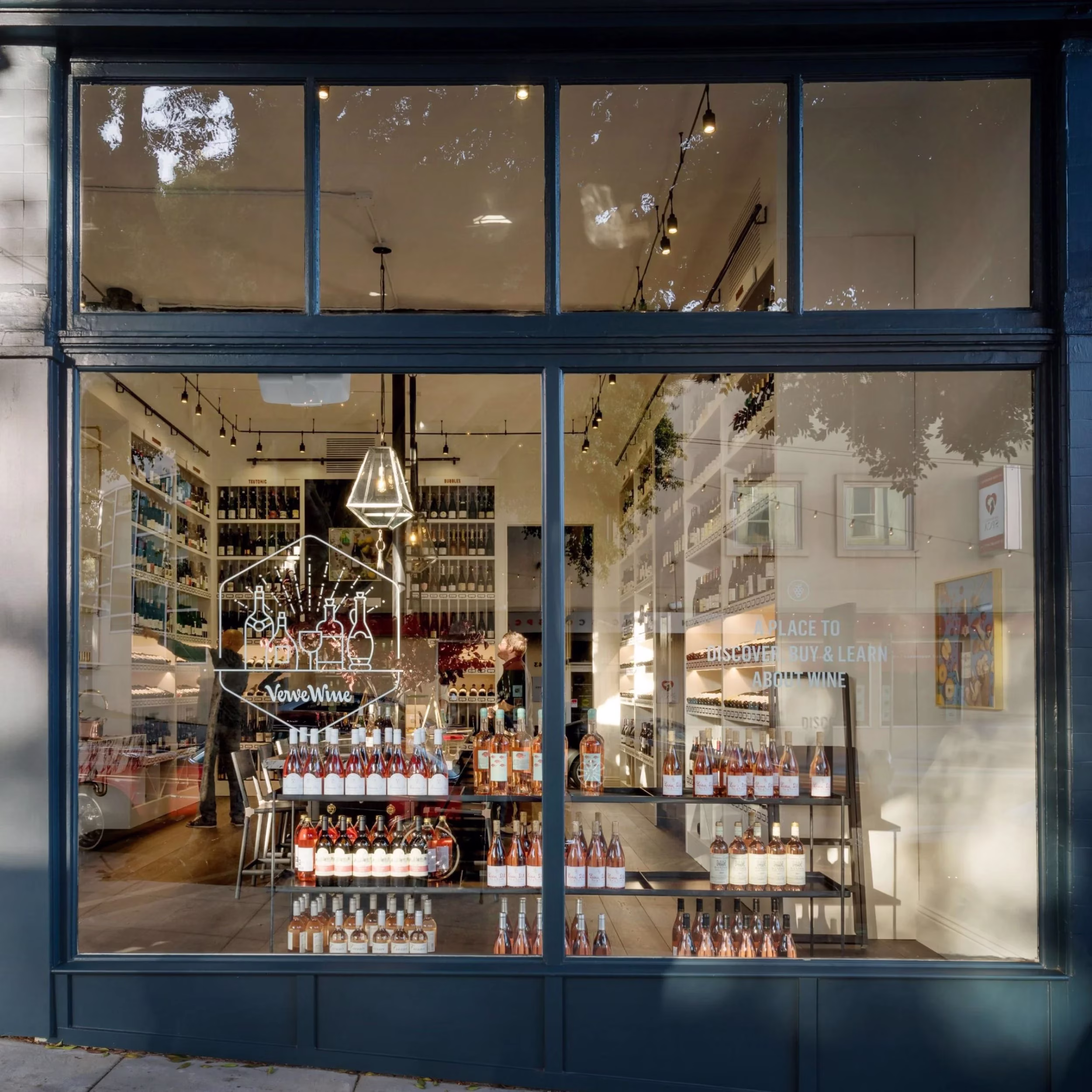 VerveWine storefront, rows of wine bottles on shelves, person inside.