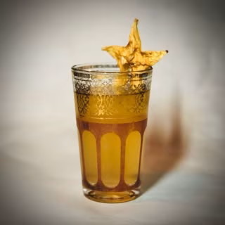 Glass of yellow drink garnished with a dried star fruit.