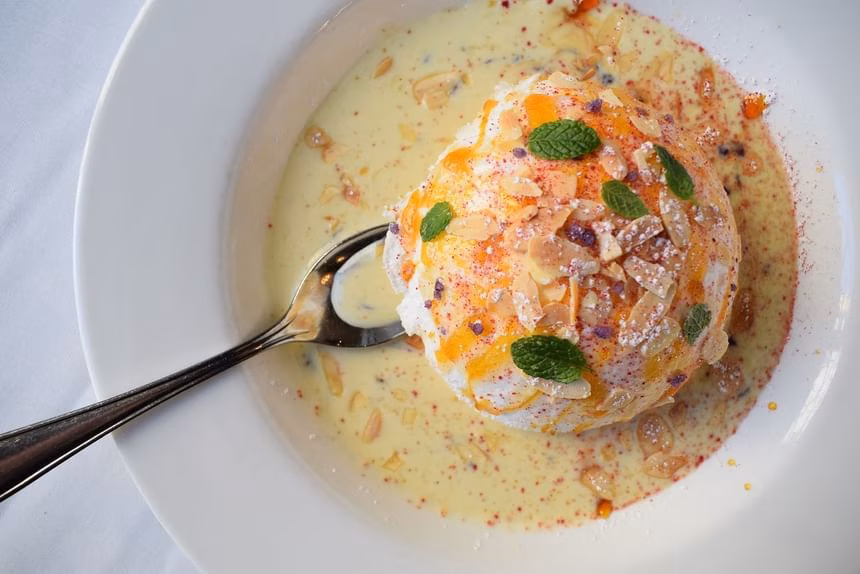 Meringue dessert with almonds, mint, and custard sauce in a bowl.