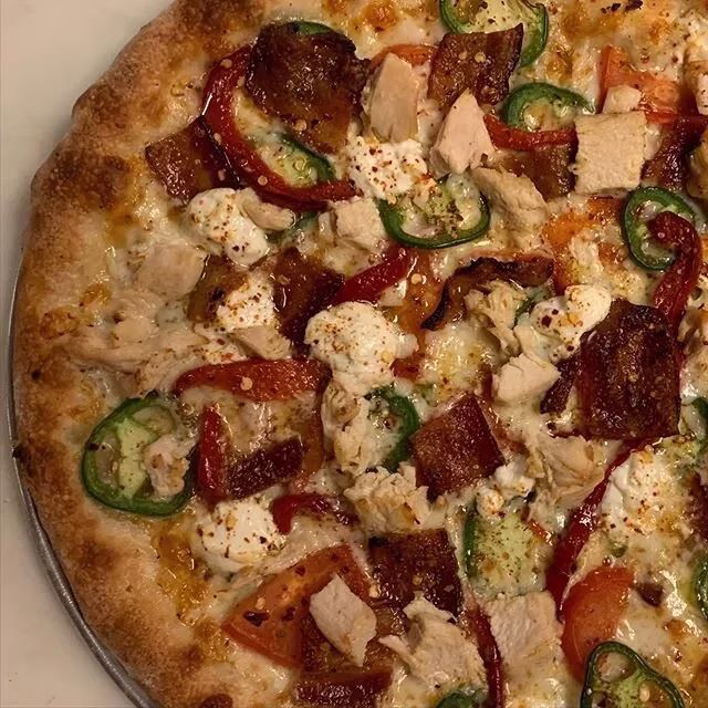 Pizza with chicken, jalapeños, red peppers, crispy bits, and white cheese.
