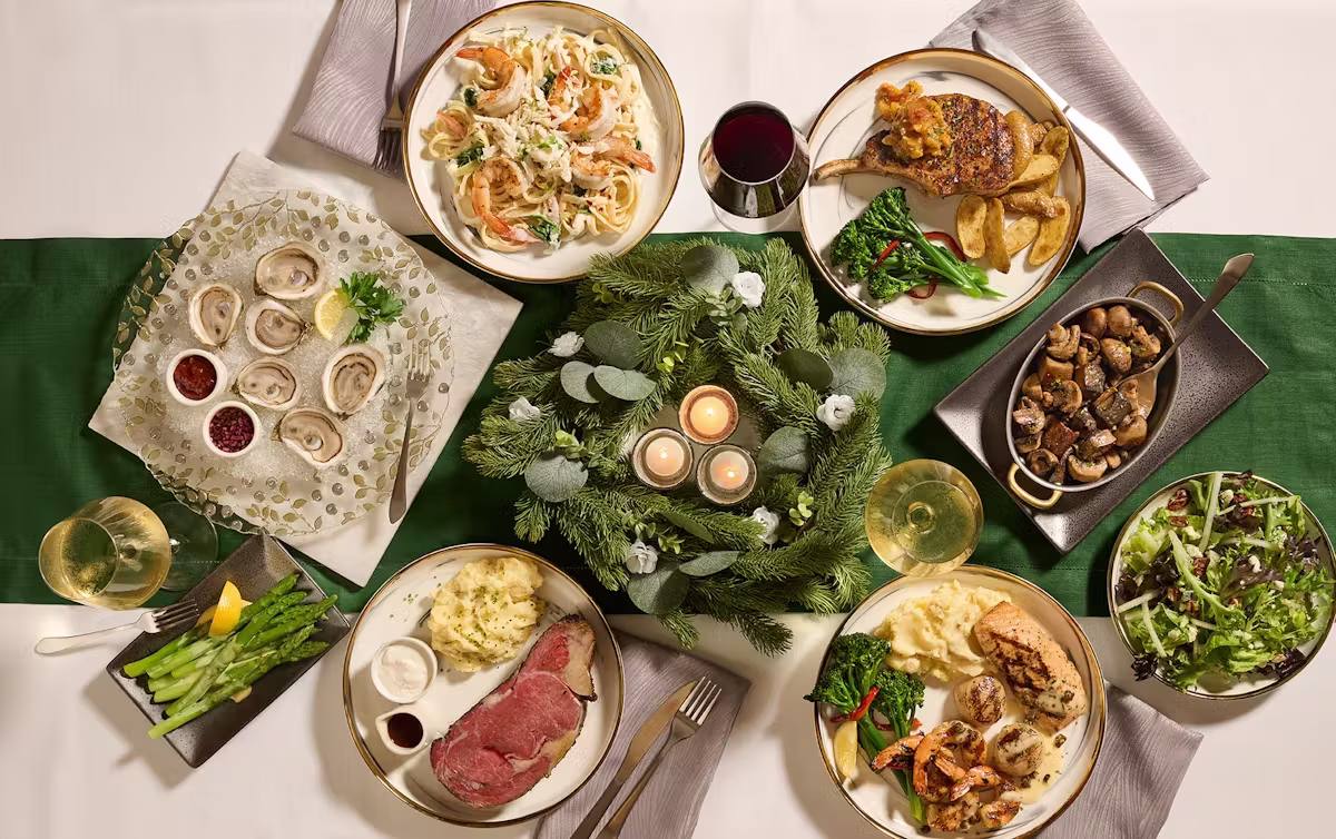 Holiday table with prime rib, seafood, pasta, and other plated dishes.