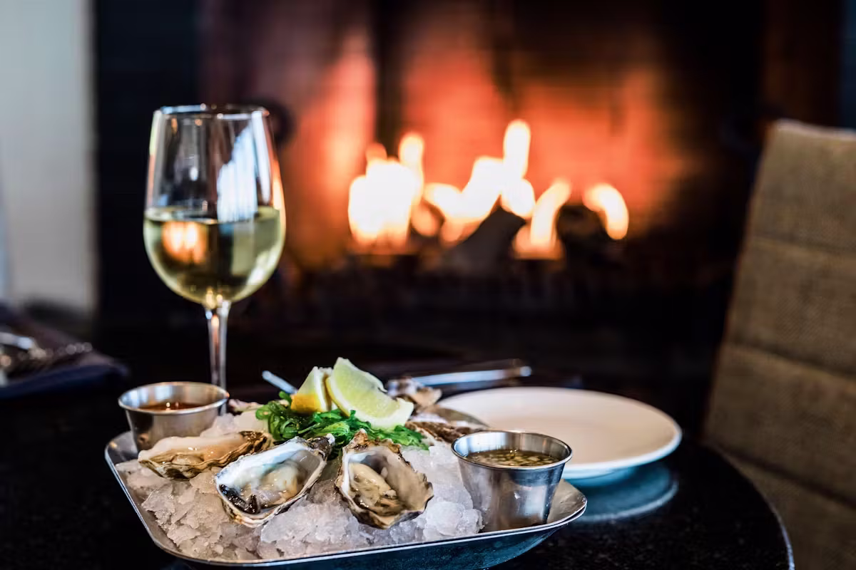Oysters on ice, white wine, and a blurred fireplace background.