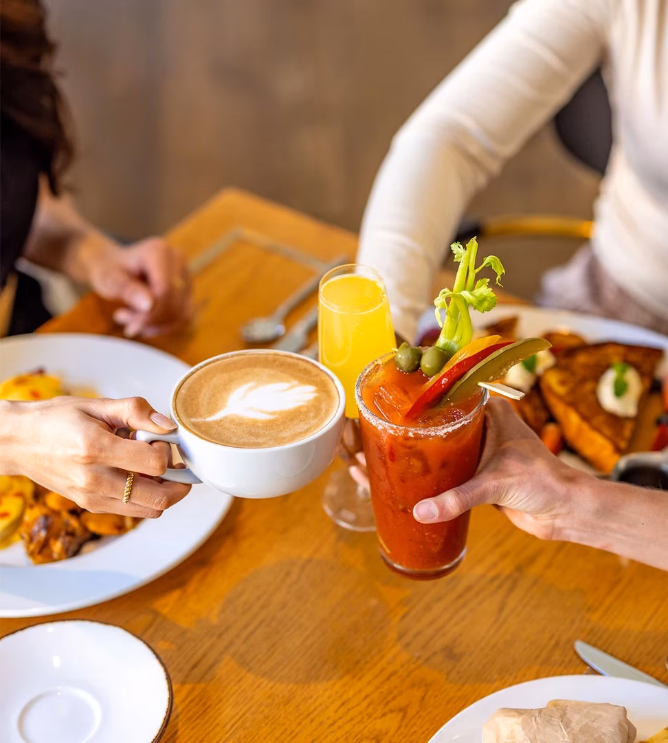 Two people toast with a latte and a Bloody Mary at brunch.