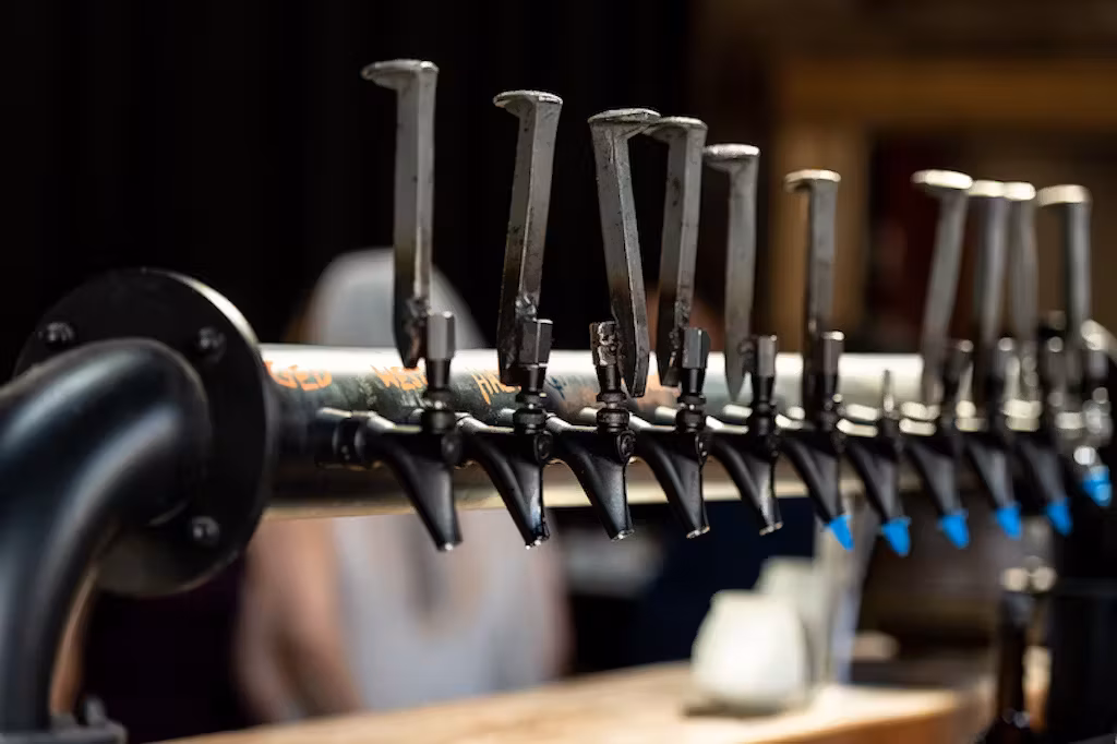 Row of dark metal beer taps with unique, industrial-style handles.