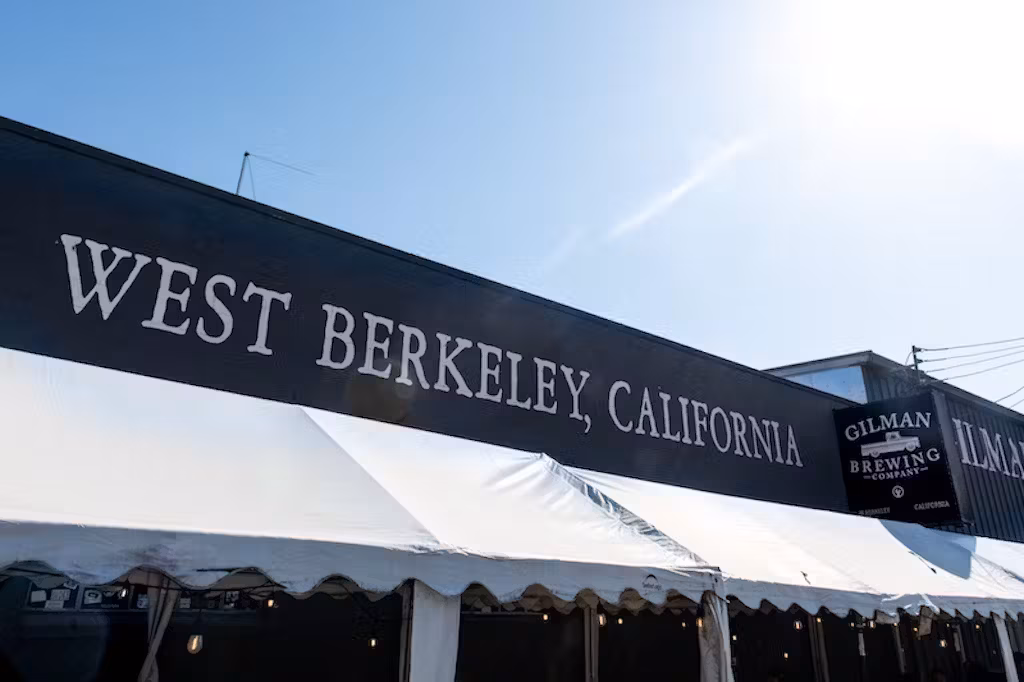 West Berkeley, California sign and white tent under clear blue sky.