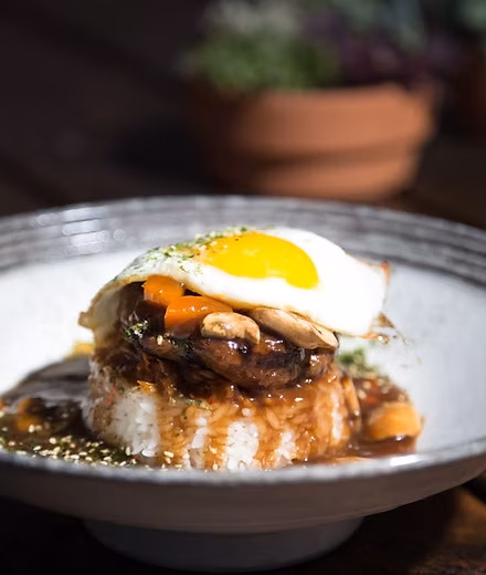 Loco moco with rice, hamburger patty, gravy, mushrooms, and fried egg.