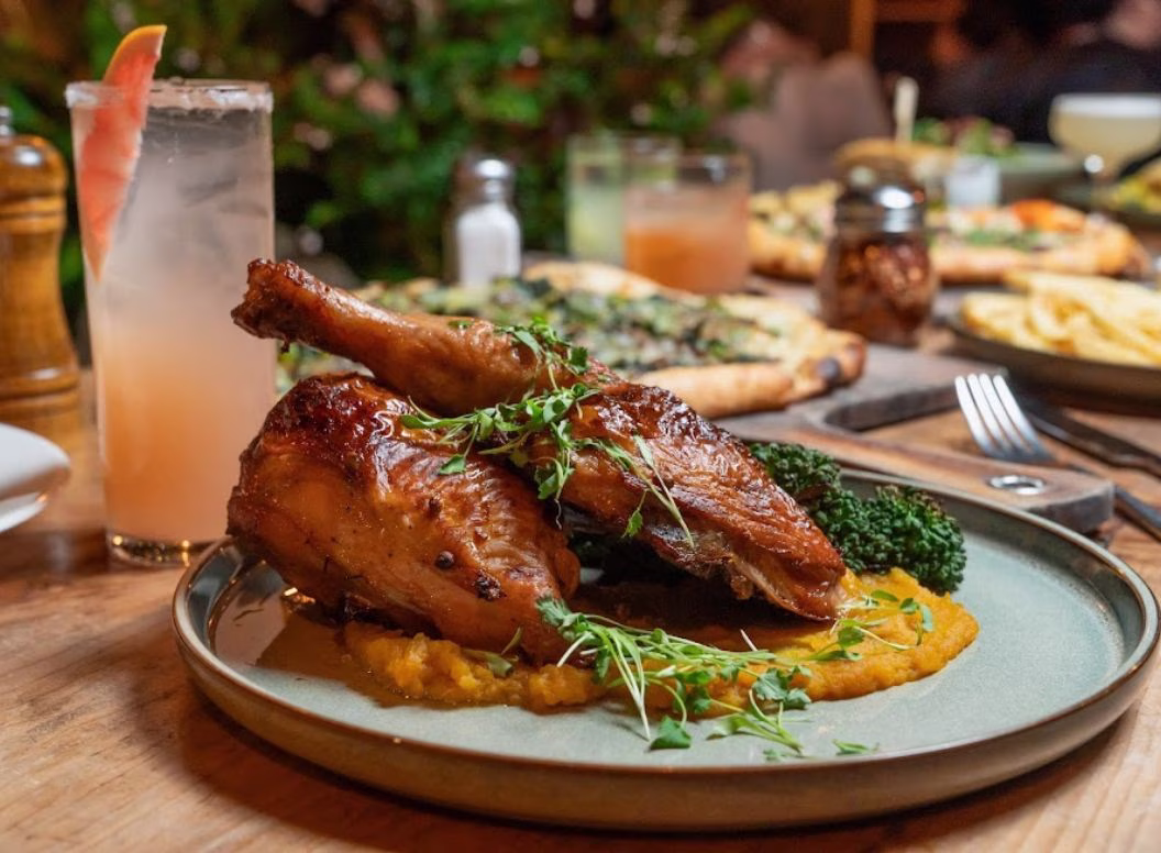 Glazed chicken pieces with mashed vegetables, broccoli, and herbs.