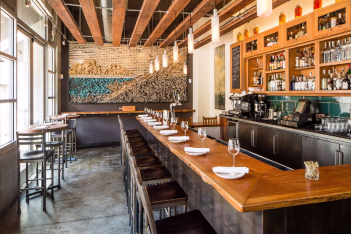 Interior of a modern restaurant with a long wooden bar and wall art.