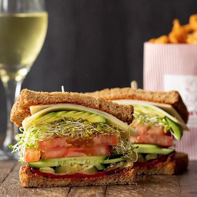 Two large whole wheat sandwiches stacked with vegetables and cheese.