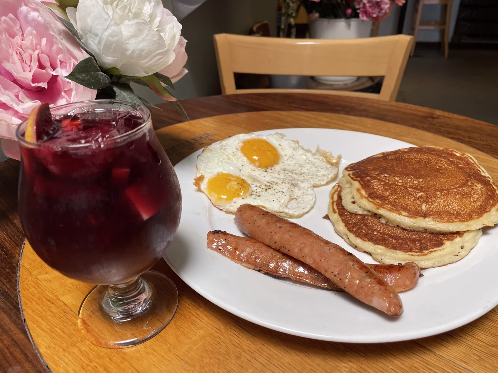 Plate of eggs, sausages, pancakes, and a glass of red sangria.