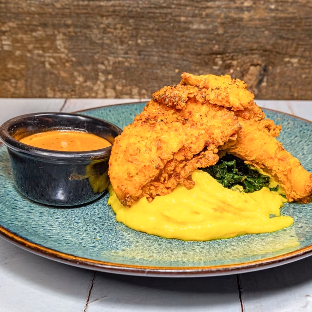 Fried chicken, yellow purée, greens, and dipping sauce.
