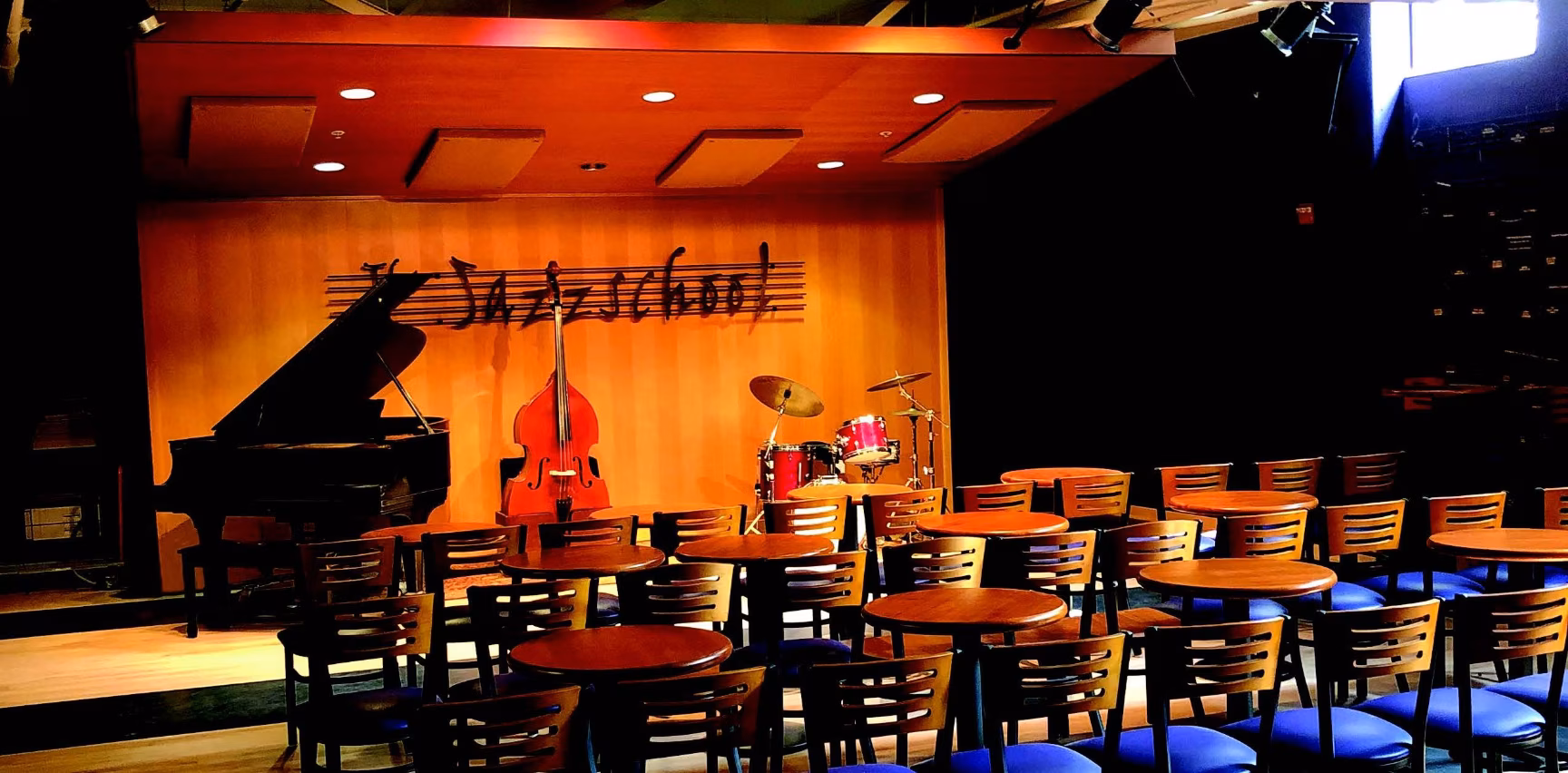 A jazz school stage with a piano, upright bass, and drum set.
