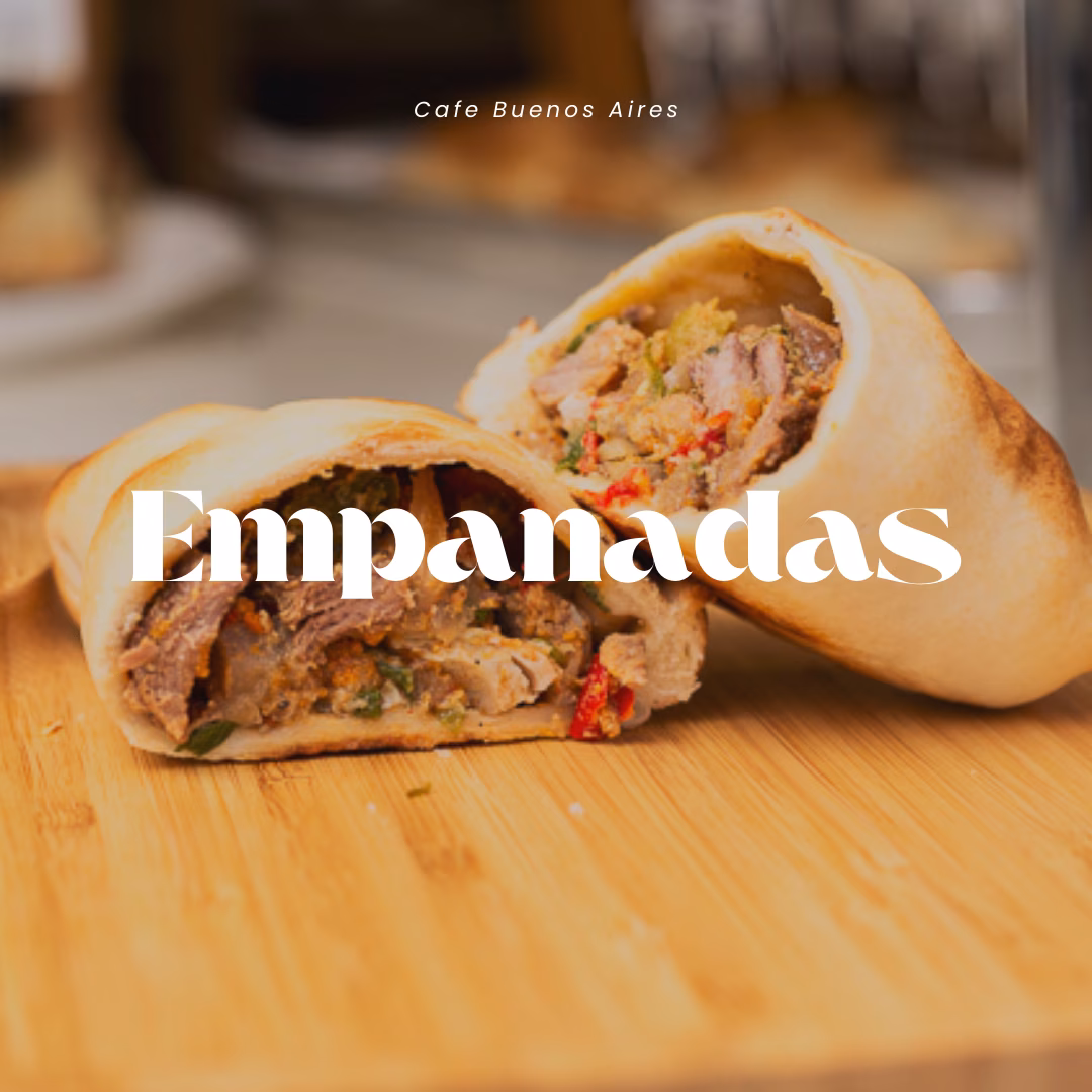 Two empanadas on wooden board, one cut open with meat filling.