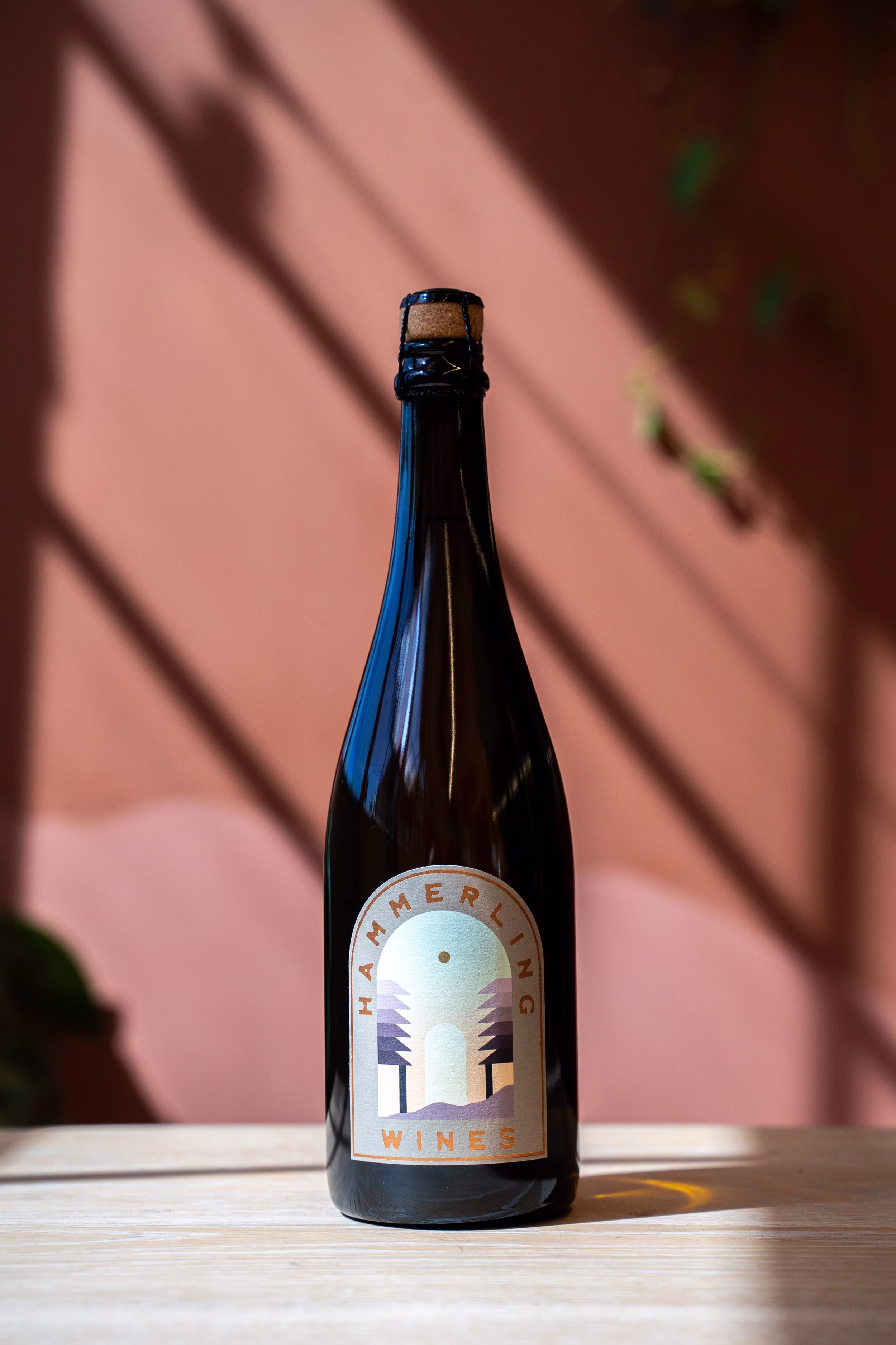 Dark bottle of Hammerling Wines with cork on wooden table.