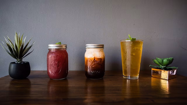 Three iced beverages and two plants on a dark wooden table.