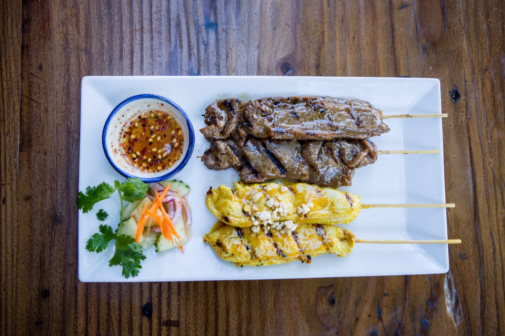 Grilled beef and chicken skewers, dipping sauce, and cucumber salad.