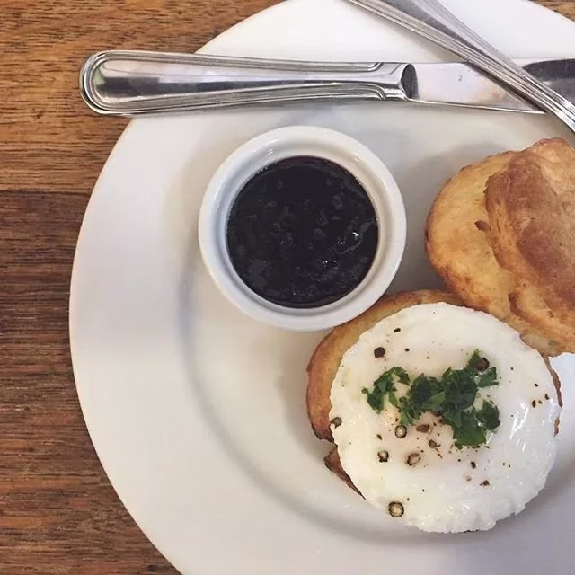Breakfast plate with a fried egg, biscuits, and dark jam.