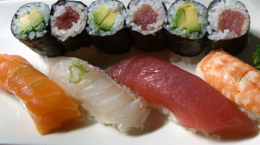 Sushi platter with maki rolls, salmon, tuna, and shrimp nigiri.