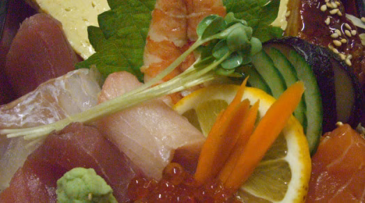 Colorful Japanese dish featuring assorted sashimi, roe, shrimp, and garnishes.