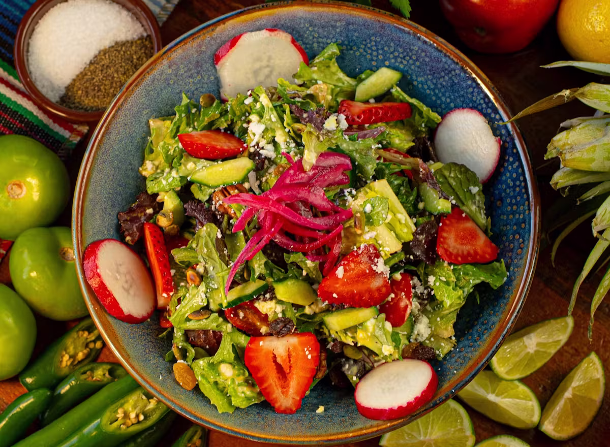Fresh green salad with strawberries, radishes, cheese, and pickled onions.