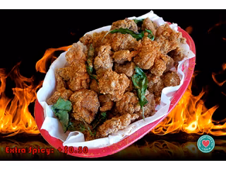 A red basket of fried chicken pieces with basil leaves and flames.