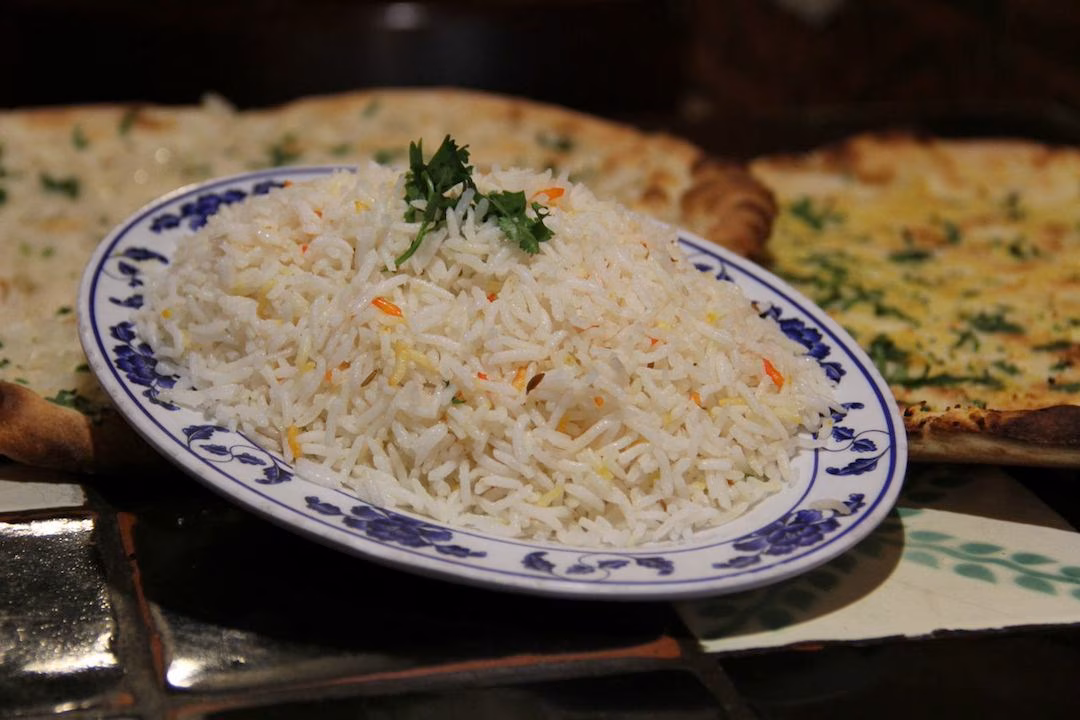 Plate of white rice with herbs, next to two flatbreads.