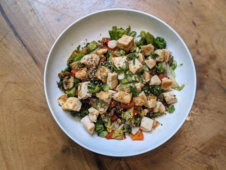 Overhead view of chicken and vegetable stir-fry in a white bowl.