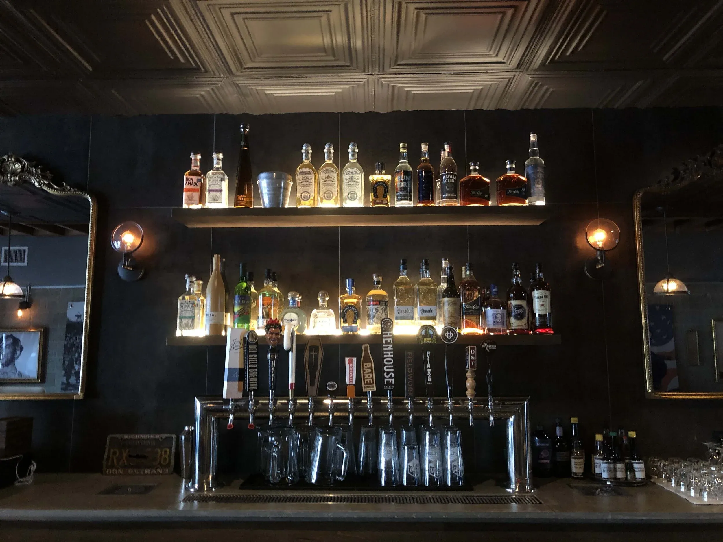 Full bar featuring backlit liquor bottles, beer taps, and ornate mirrors.