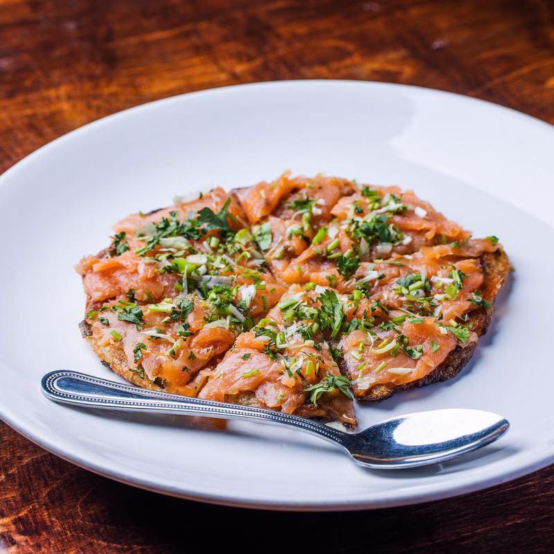 Toasted bread topped with smoked salmon, herbs, and chopped scallions.