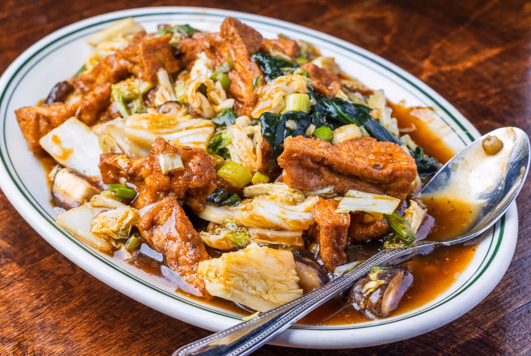 Dish with fried tofu, napa cabbage, mushrooms, and dark sauce.