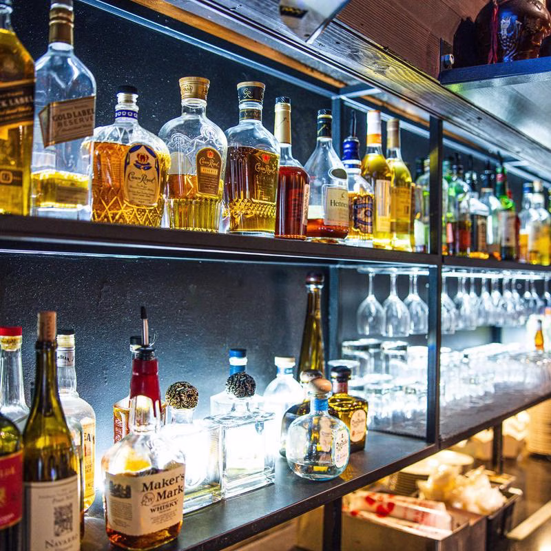 Various liquor bottles and glassware displayed on shelves in a bar.