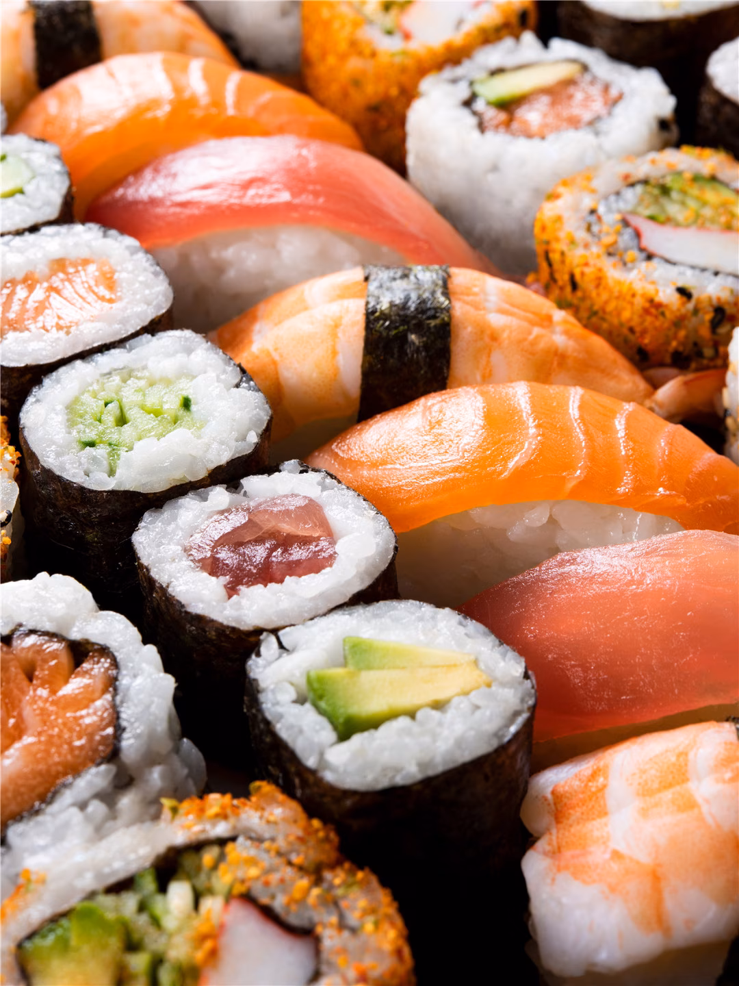 Close-up of a variety of colorful sushi rolls and nigiri pieces.