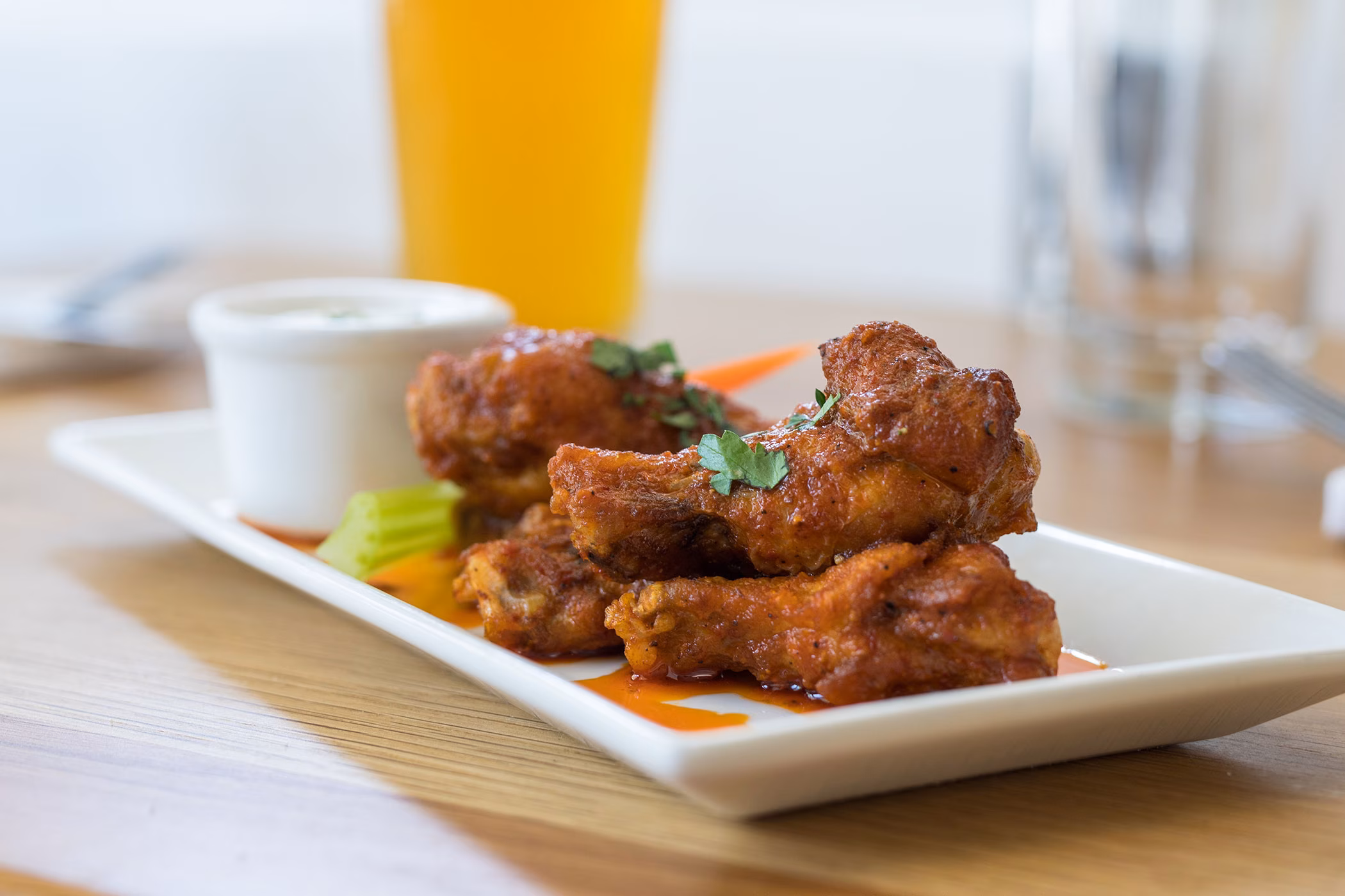 Buffalo chicken wings on a plate with celery and dipping sauce.