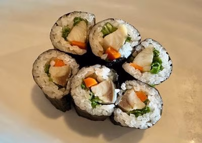 Six sushi rolls with fish, carrots, and green vegetables.
