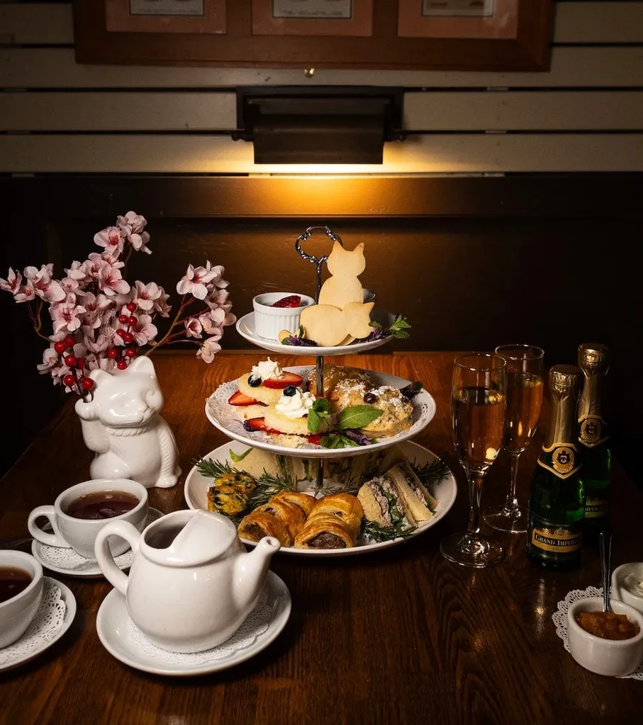 Afternoon tea with cat-shaped cookies, a tiered stand, and champagne.