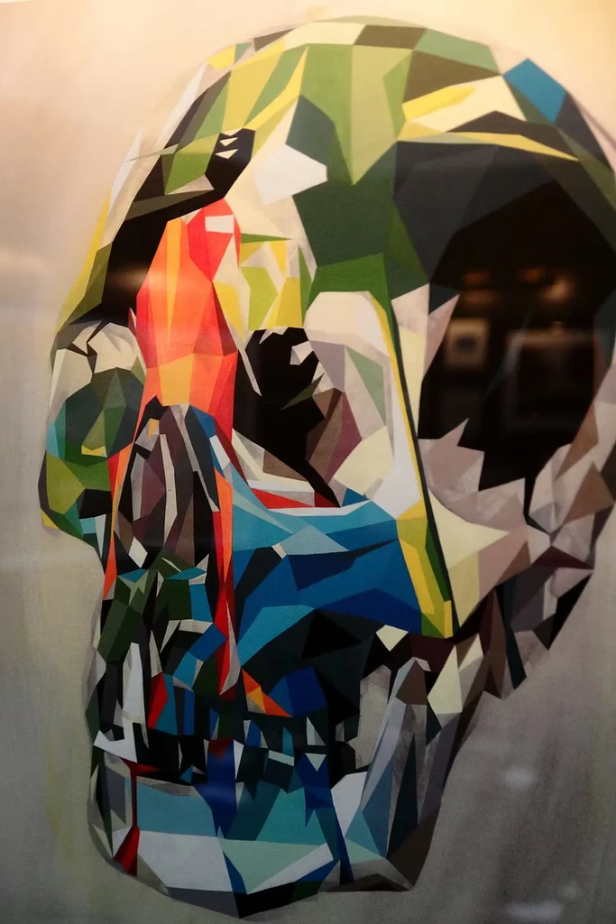 Vibrant, stylized low-poly skull artwork with geometric facets.