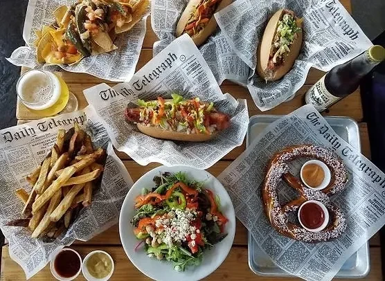 Overhead shot of nachos, hot dogs, fries, salad, pretzel, and beer.
