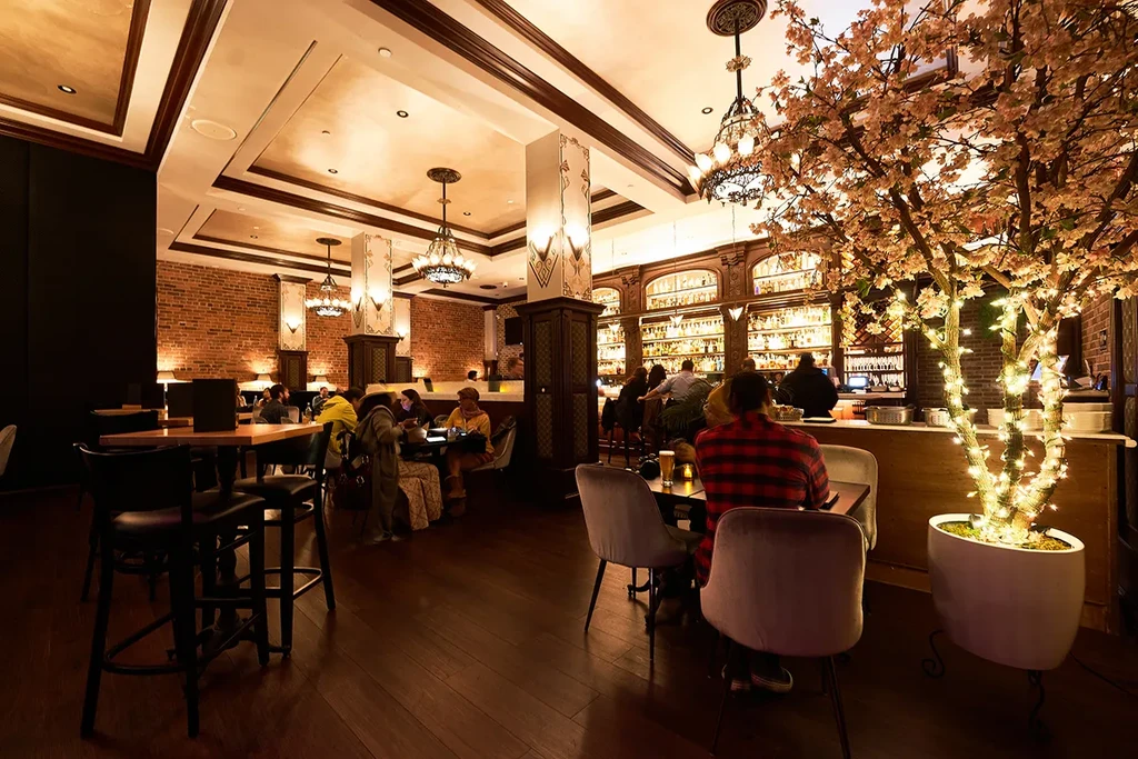 Elegant, dimly lit restaurant bar featuring dark wood and a glowing tree.